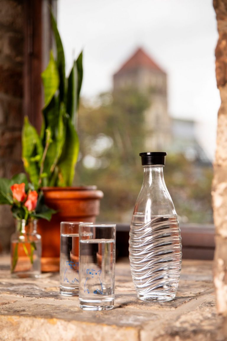 Wasserflasche und Blume im Fenster mit Nikolaikirche im Hintergrund